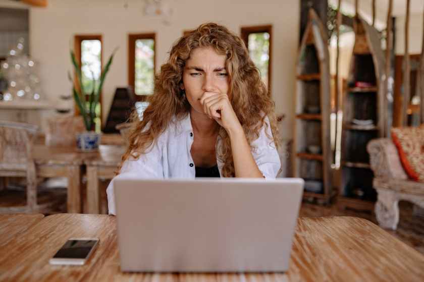 photo of woman looking serious while using laptop