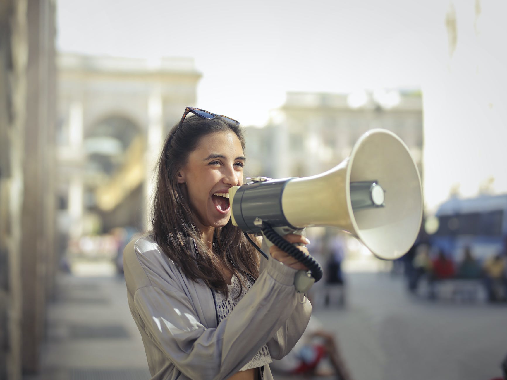 cheerful young woman screaming into megaphone (connect with your audience)