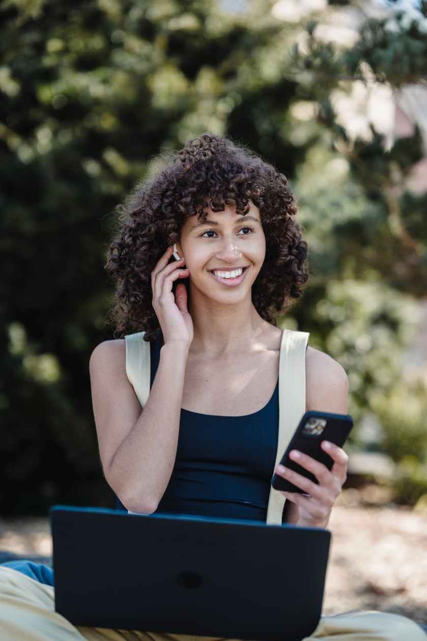 smiling ethnic woman with smartphone working in nature