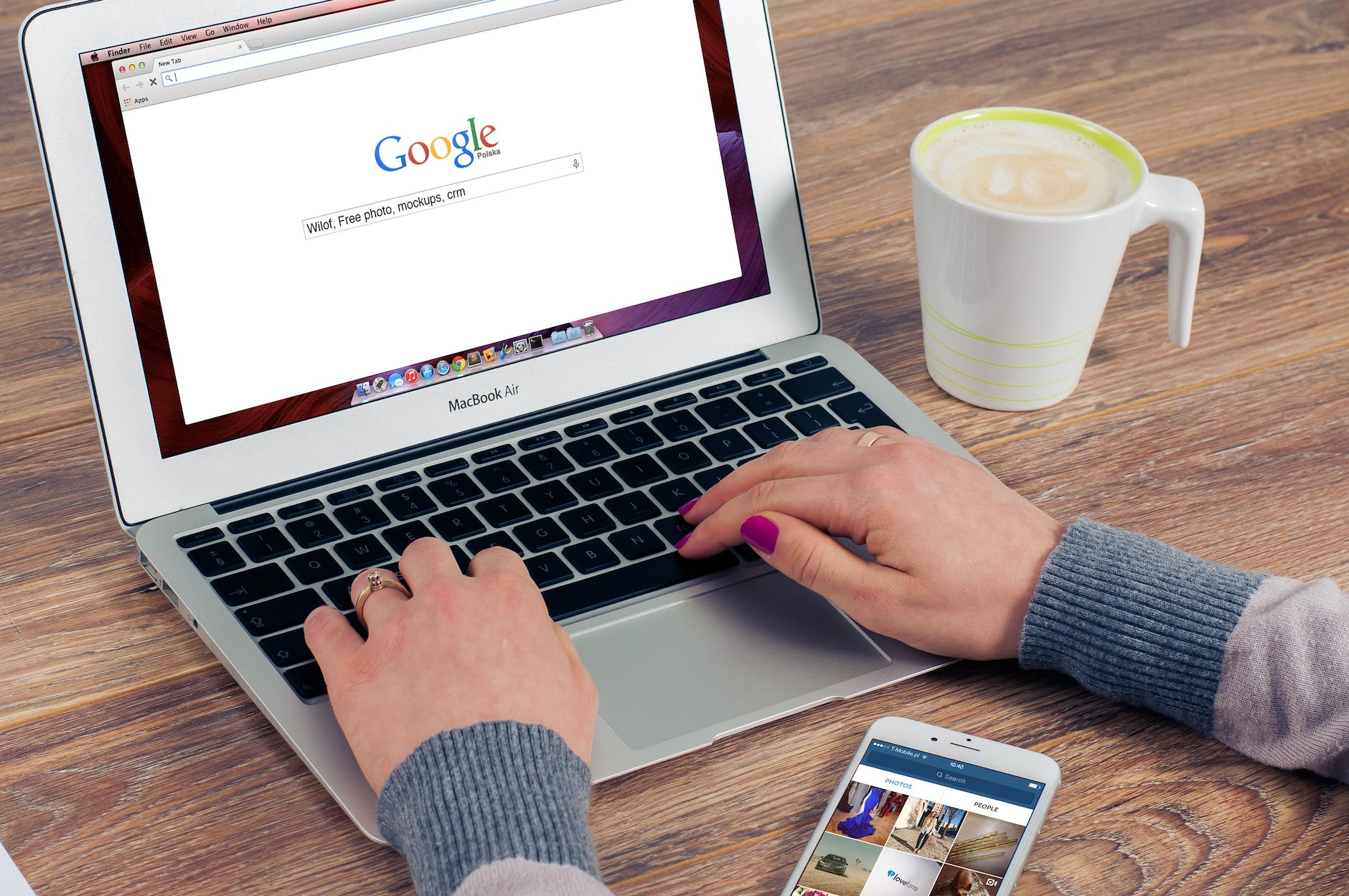 Someone typing on a laptop into Google. There is a coffee and an iphone on the table. This article is for SEO based content writing.